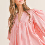 A pale pink poplin fabric, the Mariah Dress features puff sleeves and a pleated mini design. With delicate front button detail, this dress is both chic and versatile, perfect for any occasion. Elevate your wardrobe with this must-have piece.