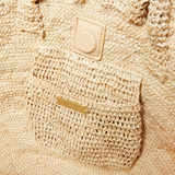 Open tote bag with ruffled detailing in natural crocheted raffia. Features top handle straps and a magnetic closure.
