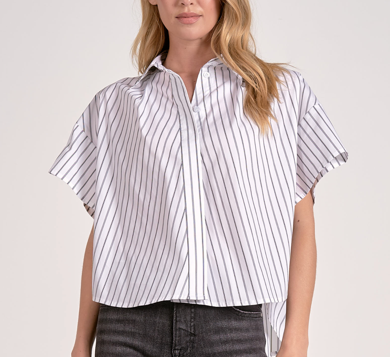Woman wearing a white and gray striped shirt with short sleeves on a plain background