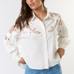 Woman wearing a white blouse with lace details and blue jeans on a white background