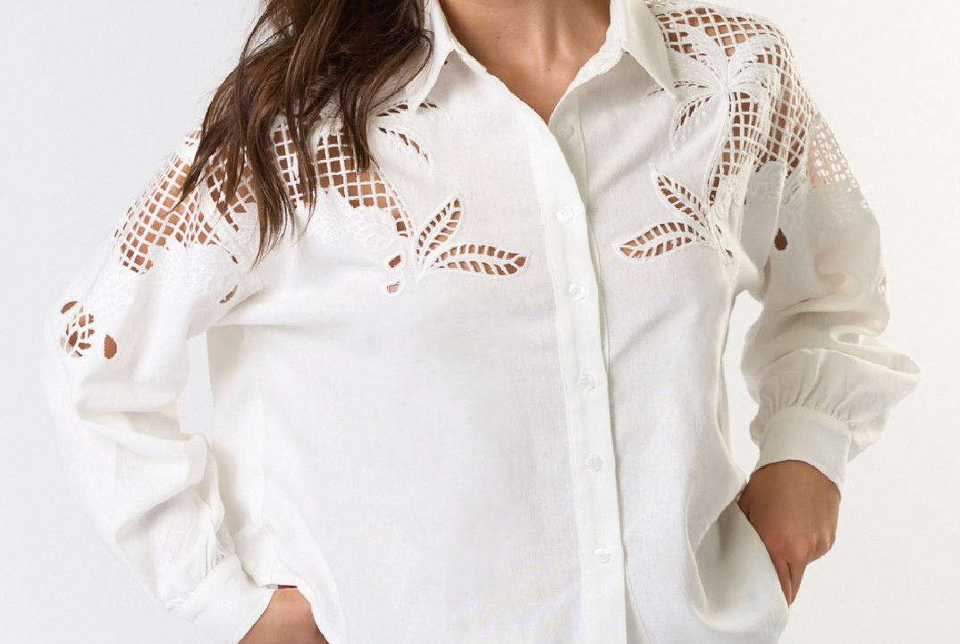 Woman wearing a white blouse with lace details and blue jeans on a white background