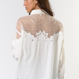 Woman wearing a white blouse with mesh back design on a white background