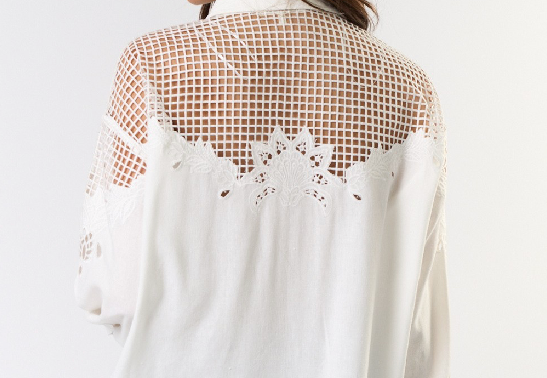 Woman wearing a white blouse with mesh back design on a white background